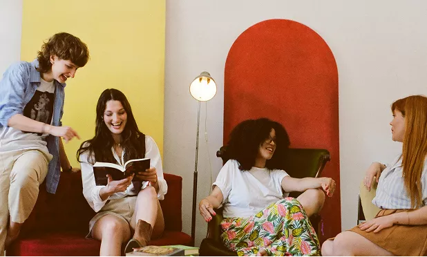 Unlike the others, this is a candid-style photograph of four people in a brightly colored room. It feels natural and focuses on human connection and shared learning.